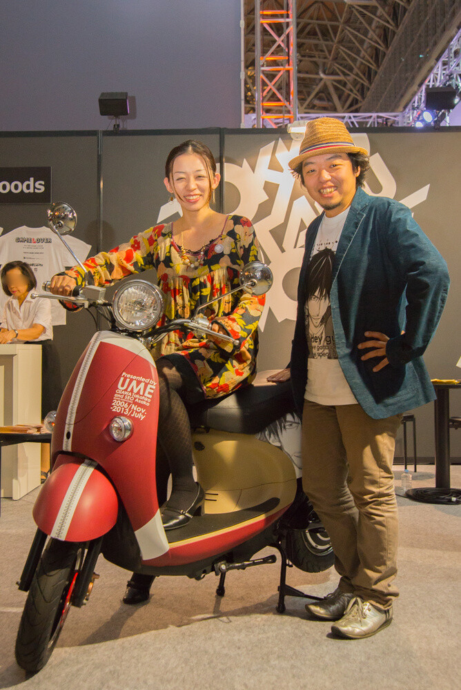 The manga artist combo looking delighted posed with a scooter themed after the jersey worn by the main character of *Tokyo Toy Box*, Taiyo. 12