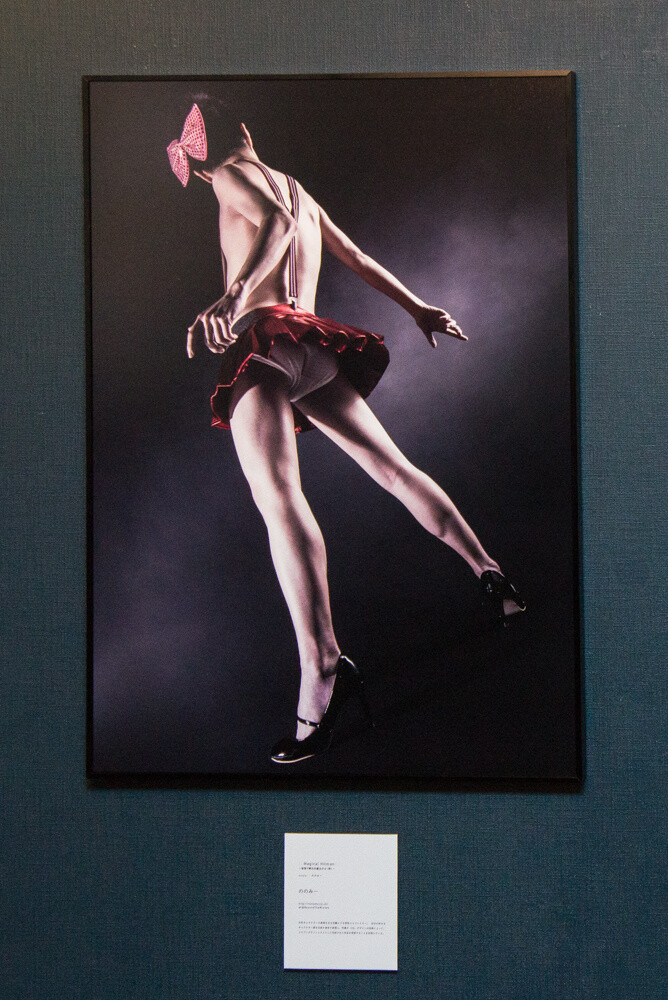 “Magical Hitman ~The Young Witch (Man) Who Solves Things with Physics~” by Nonomy. Comment from Nonomy: “This photograph shows a man wearing a green shirt (me) looking at the main visual for Panchira 2015, and I transform into a young witch (man). Usually, the focus is on women characters, but I boldly used a man’s form for viewers to enjoy the gap between what is expected and what is presented. Please pay attention to the nicely shaped legs extending from the schoolgirl’s shorts.” © Nonomy 18