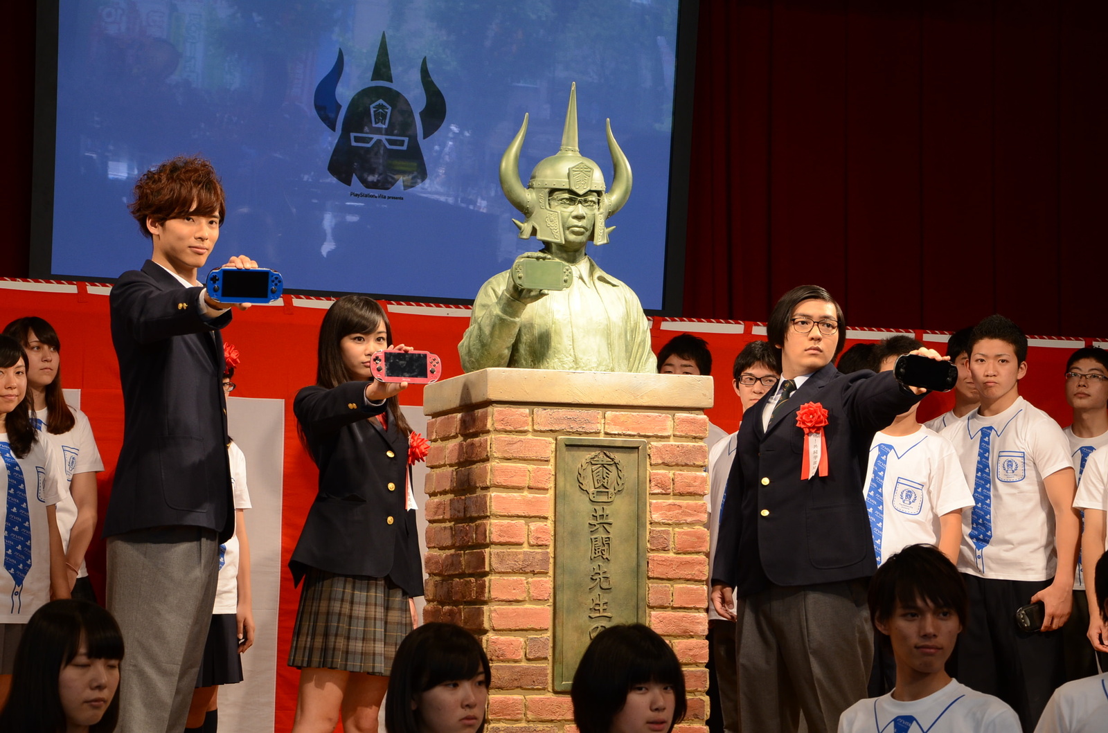 The three stars from the CM posed in front of a bronze statue of Kyoutou Sensei.  15