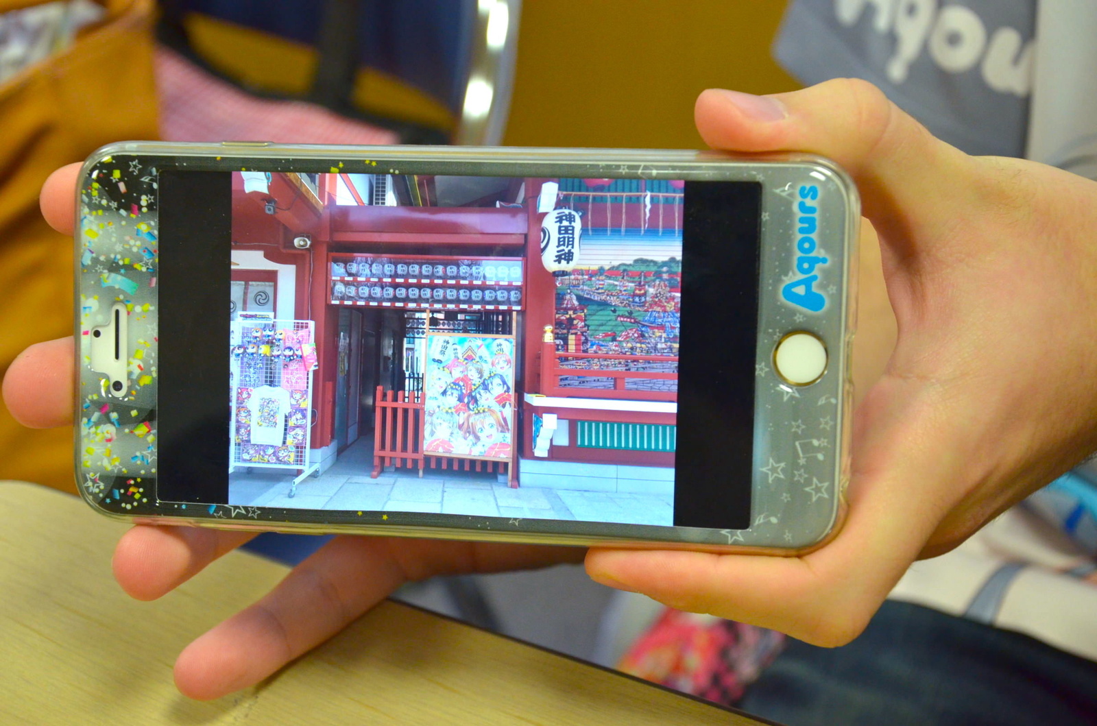 The photo shows a μ’ｓposter that decorated Kanta Shrine. Naturally, Andrei’s smartphone has an Aqours cover. 7